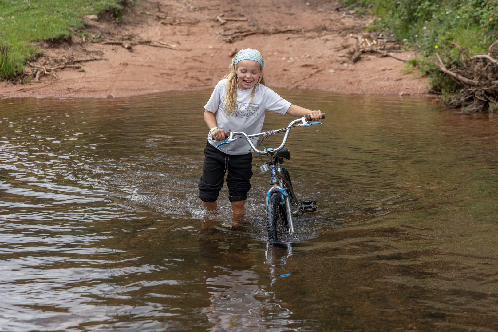 A young guest pushing her bike through the creek crossing