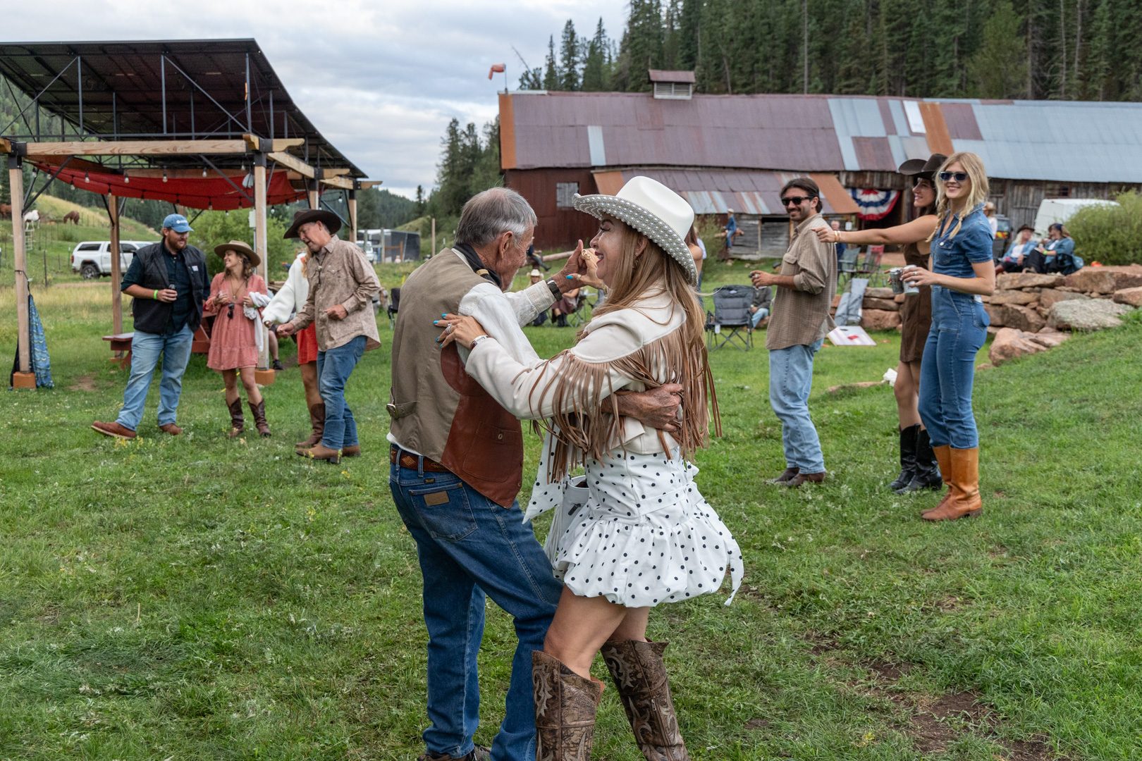 A couple dancing in the meadow with the barns behind them