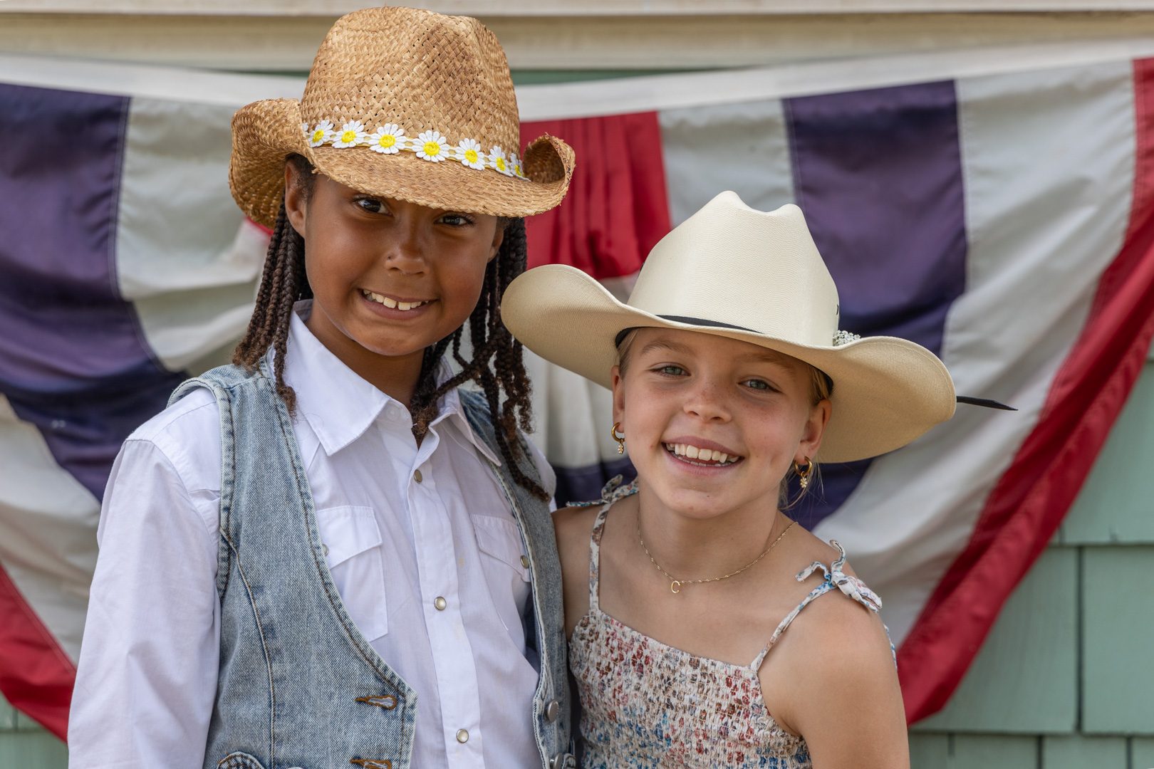 Two young guests in cowboy hats grinning in front of the bunting