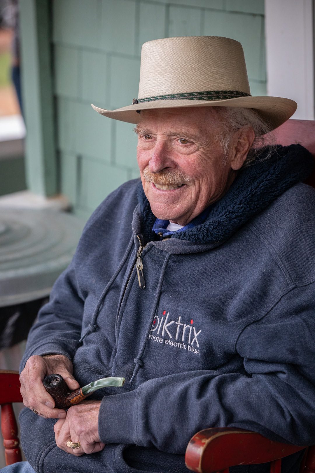 An old rancher in a cowboy hat smiling on the lodge porch