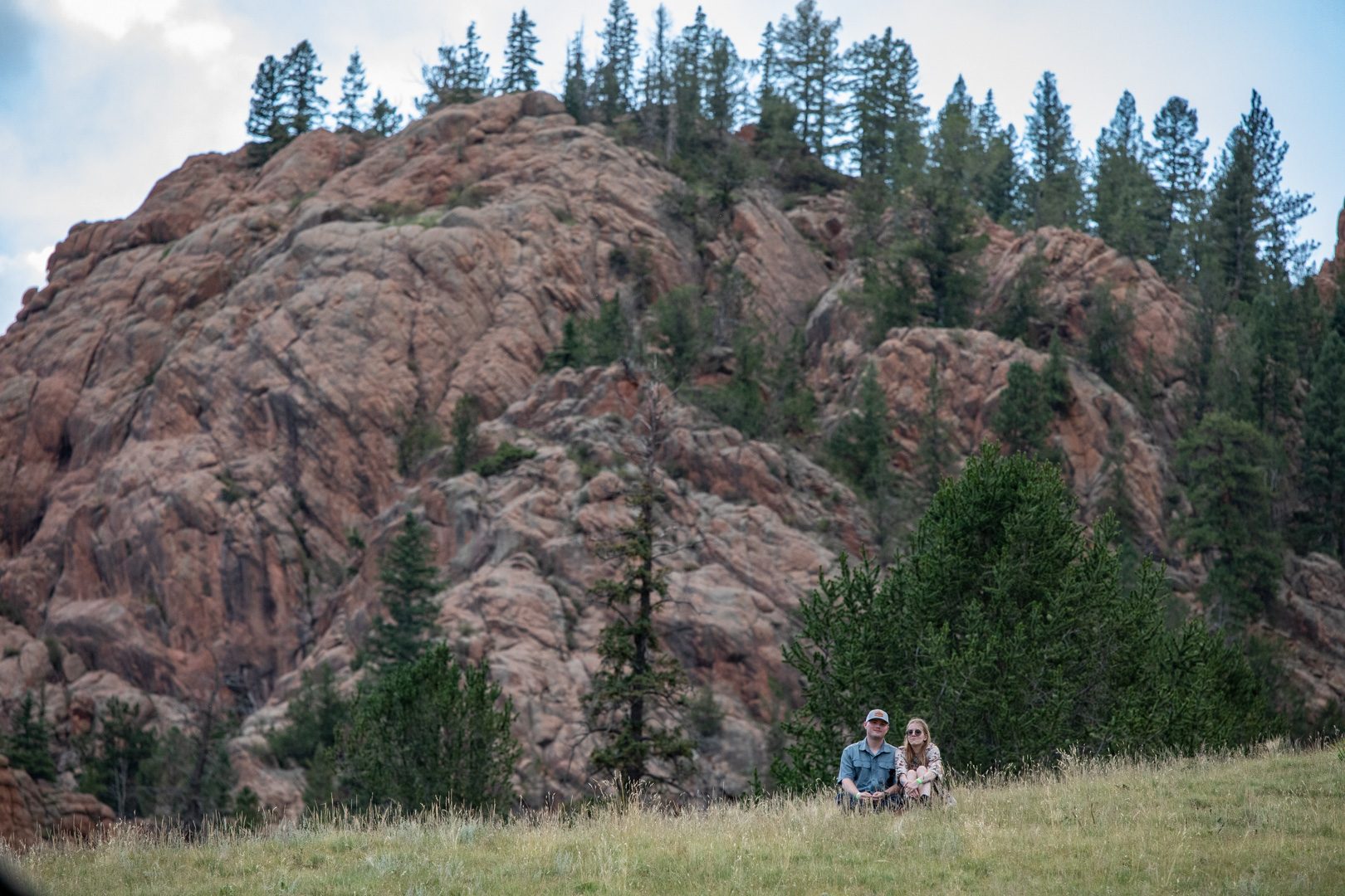 Two guests sitting in the meadow below a granite outcrop