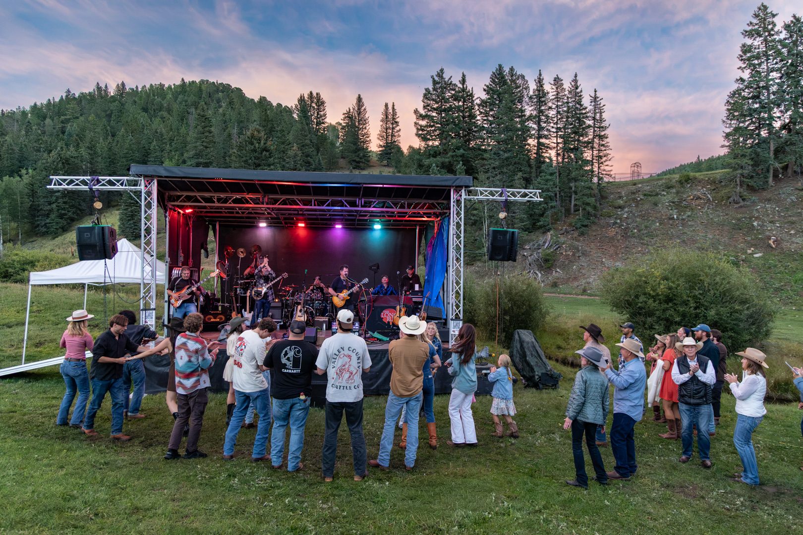 A crowd dancing in front of the meadow stage at sunset during the August barn dance