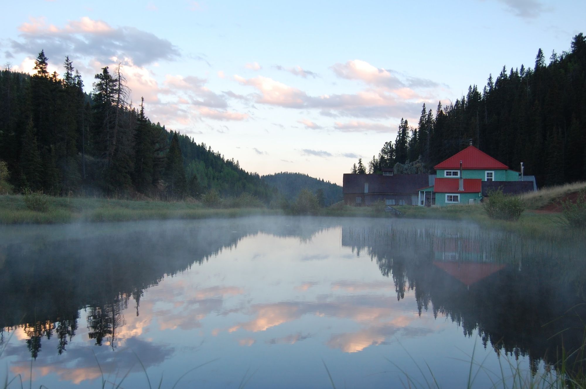 The ranch lodge, a restored miner's hotel, across the still pond on a misty morning