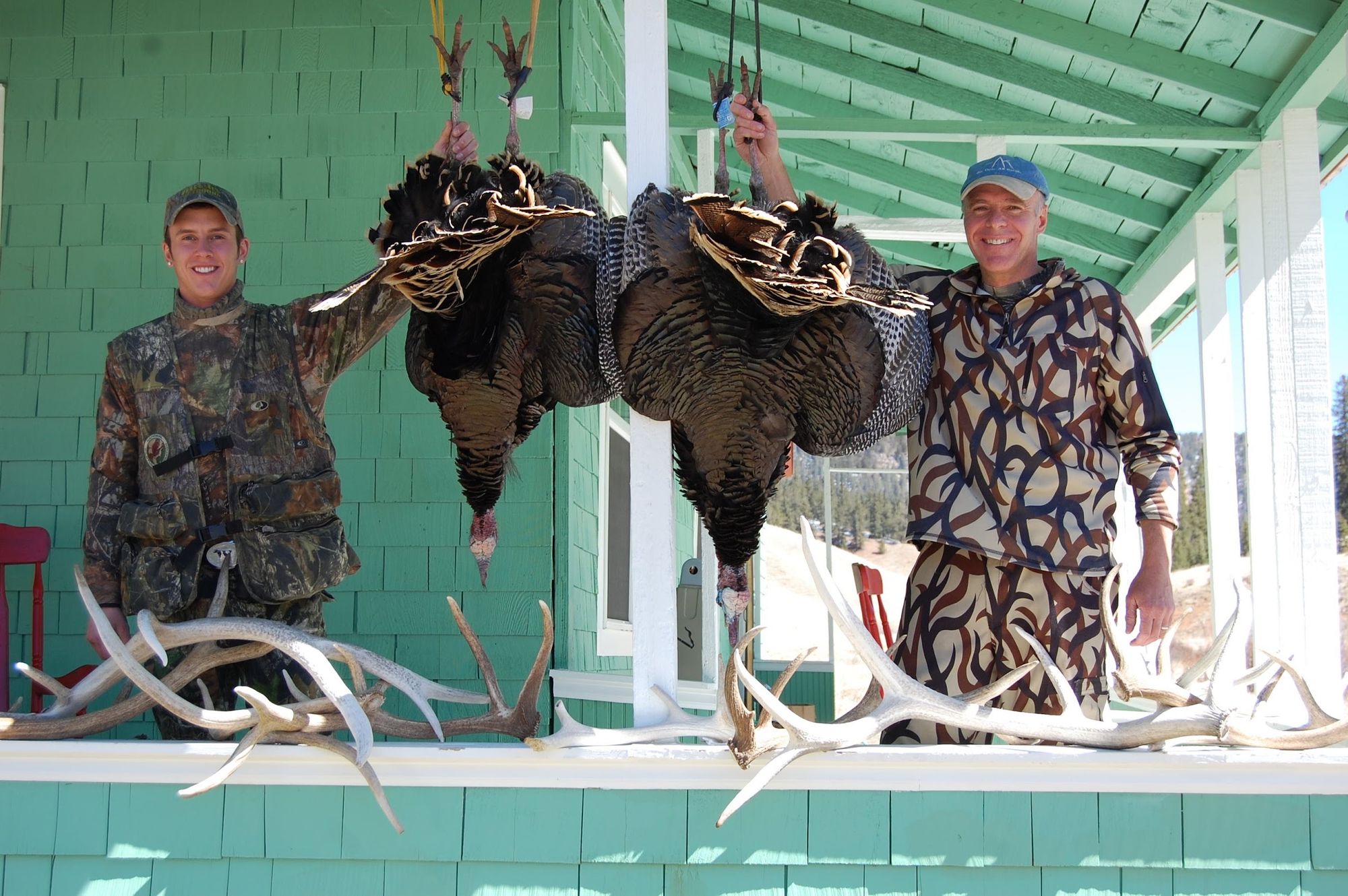 Two hunters with their spring toms on the lodge porch at Elk Glade