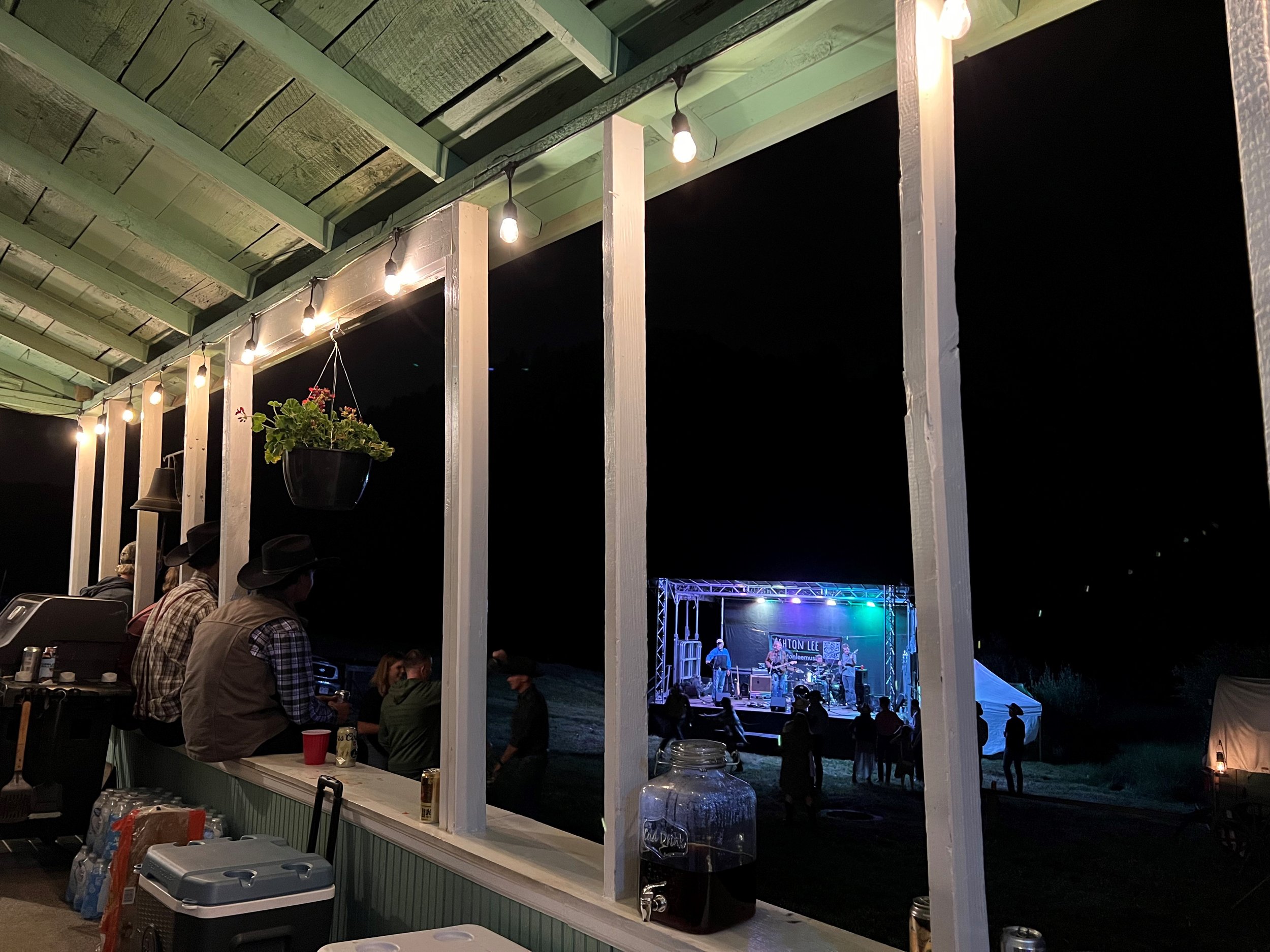 The lodge porch at night with the band playing on the meadow stage beyond